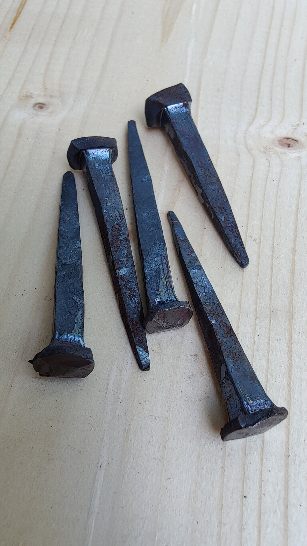 5 forged nails on a wooden surface