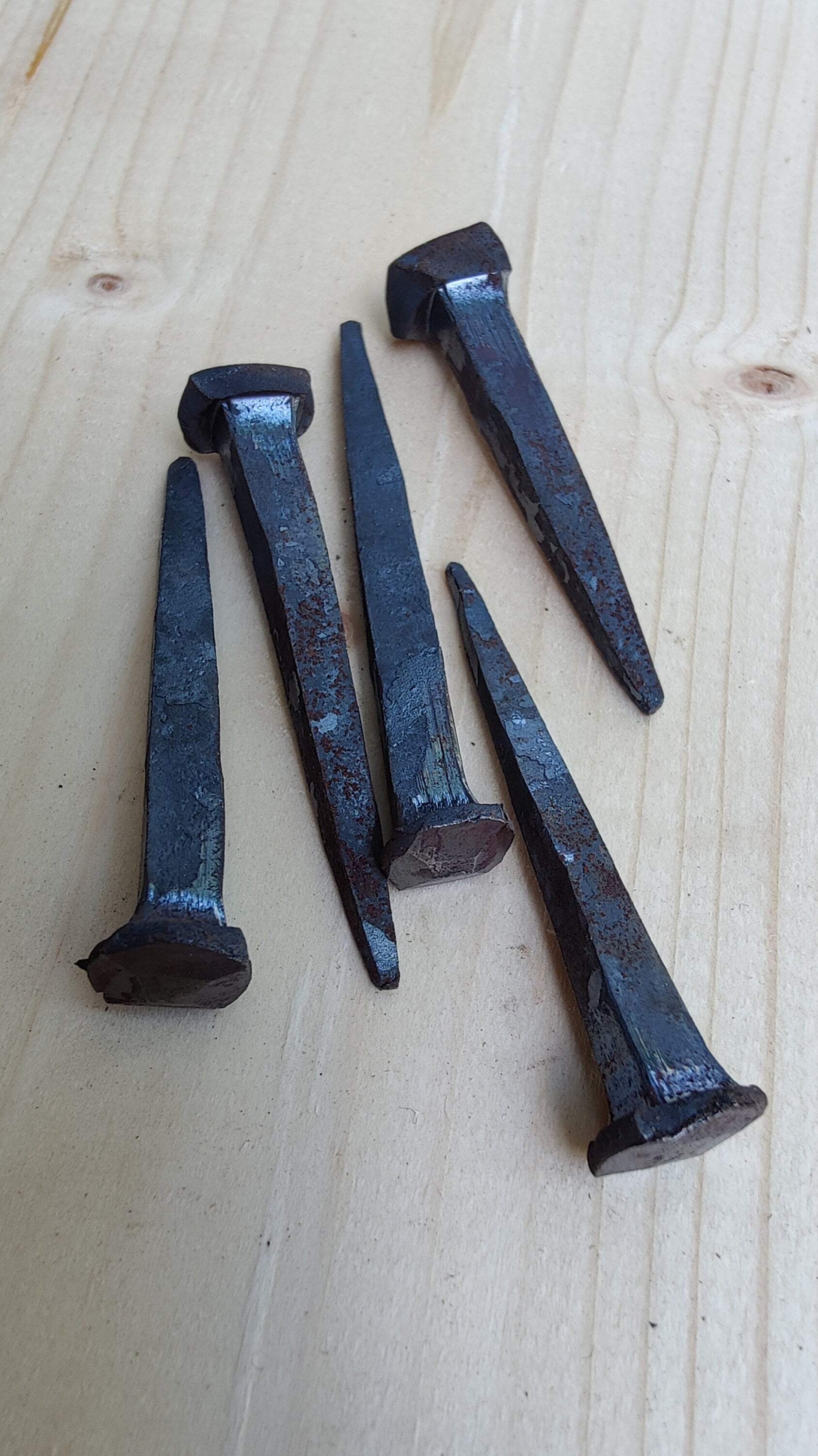 5 forged nails on a wooden surface